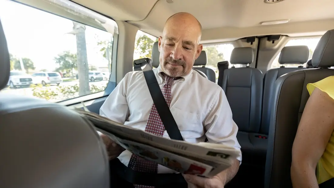 Man reading newspaper on van