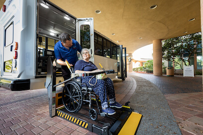 helping woman in wheelchair off bus